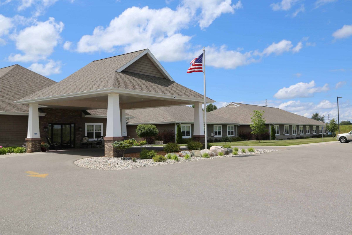 A building entrance with a flagpole and an American flag on a clear day.
