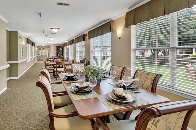 An elegantly set dining area with multiple tables and chairs, featuring large windows that allow natural light to fill the space.