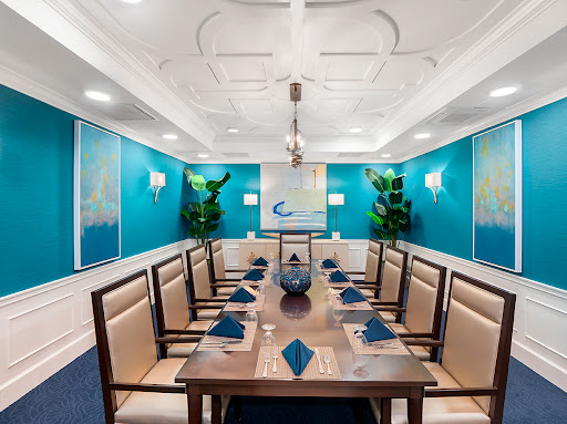 A sophisticated dining room with a modern design featuring a large conference table, elegant seating, and vibrant blue walls.