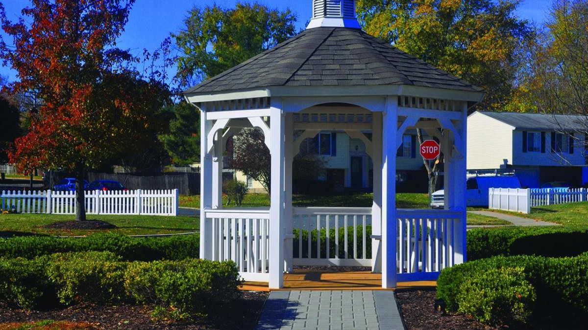 A charming white gazebo stands in a landscaped garden.