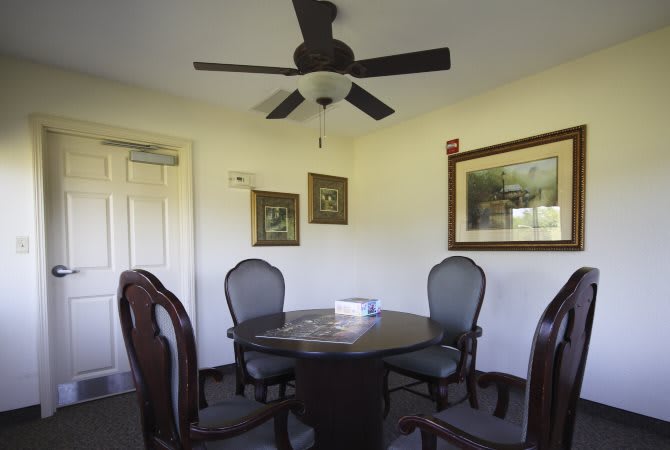 A cozy dining room with a round table, surrounded by four chairs and adorned with paintings on the walls.