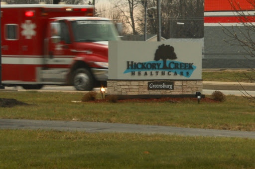 An emergency vehicle passes by the Hexwood Creek Healthcare sign, indicating a facility dedicated to health services.