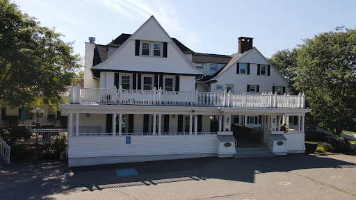 A charming two-story white house with a spacious deck, showcasing classic architectural features.