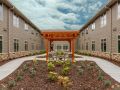 A beautifully landscaped courtyard with a wooden arbor and modern buildings on either side.