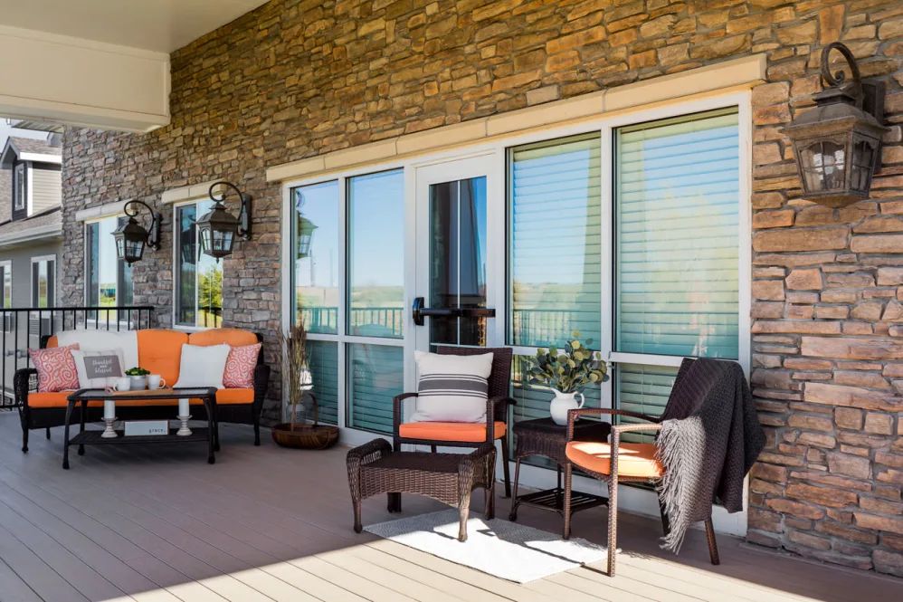 A cozy patio setup with outdoor furniture against a stone wall.