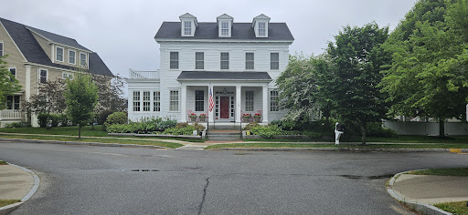 A charming two-story white house with a welcoming front porch and a beautifully landscaped garden.