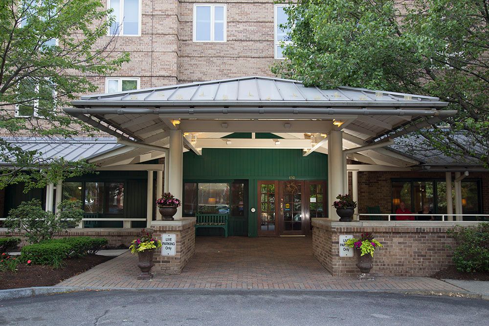 The entrance of a hotel with a covered walkway and surrounding greenery.