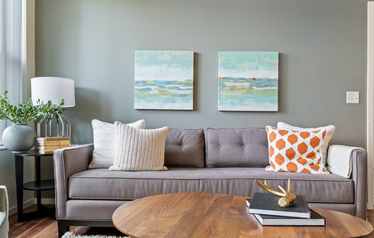 A cozy living room with a gray sofa adorned with patterned pillows and modern wall art.