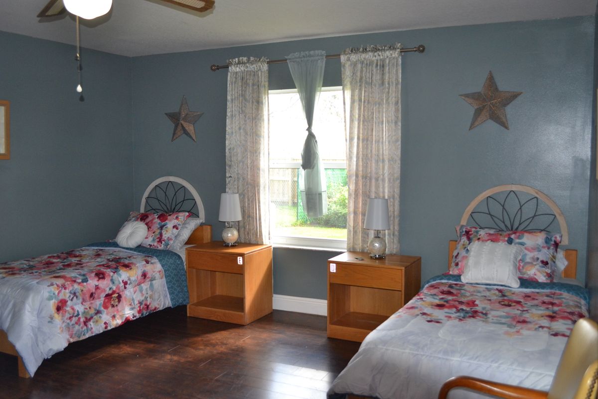 A cozy bedroom with twin beds and blue walls, featuring wooden furniture and decorative elements.