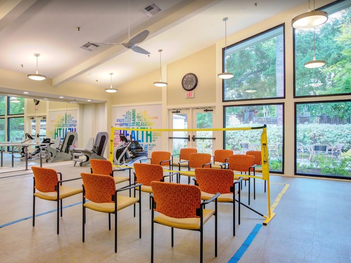 An indoor exercise room with gym equipment and a seating area.