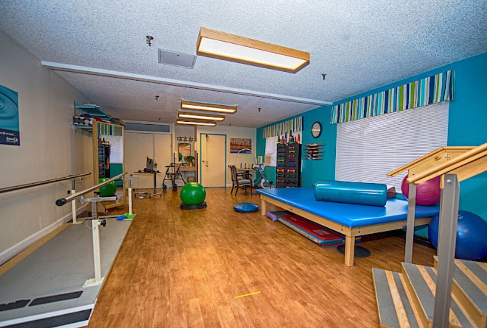 A well-equipped physical therapy room featuring exercise equipment and treatment tables.
