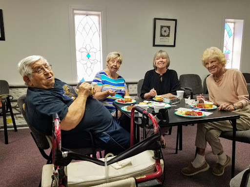 A group of four elderly individuals enjoying a meal together in a cozy setting.