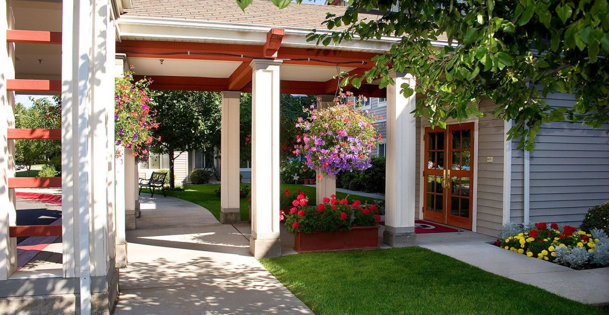 A beautifully landscaped entrance with hanging flower baskets and neatly trimmed grass.