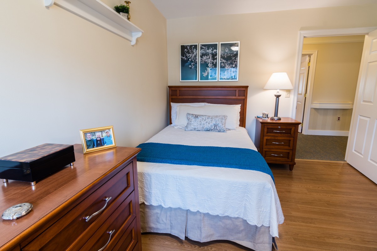 A cozy bedroom with a single bed, featuring blue accents and wooden furniture.