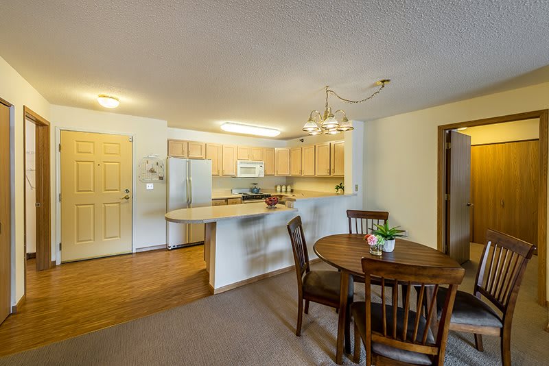 A cozy open-plan kitchen and dining area with wooden furniture and modern lighting.