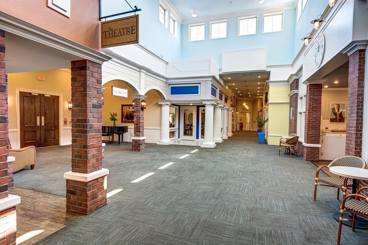 A spacious and brightly lit shopping mall interior with multiple storefronts along the hallway.