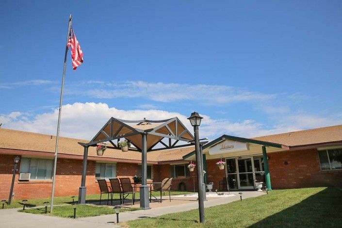 An outdoor view of a building entrance with an American flag and patio seating area.