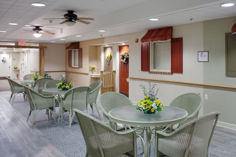A cozy indoor seating area with tables decorated with flowers.
