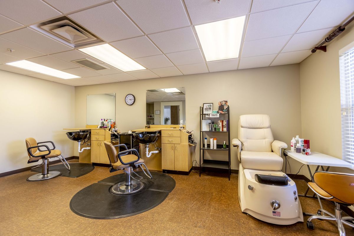 A modern hair salon interior featuring barber chairs, a spa chair, and a mirror.