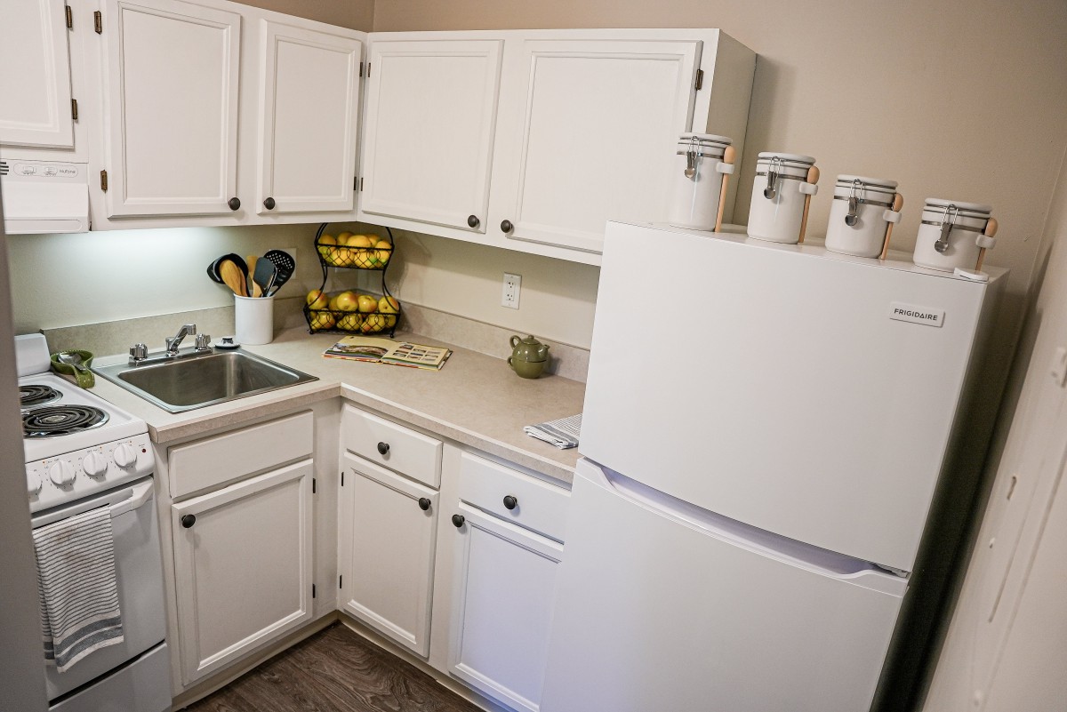 A neatly organized kitchen with white cabinets and a refrigerator.
