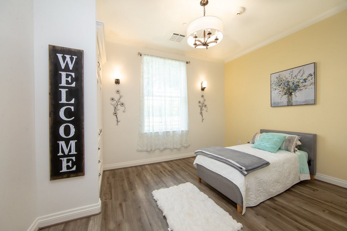 A cozy and minimalistic bedroom with a single bed, featuring wooden floors and a welcoming atmosphere.
