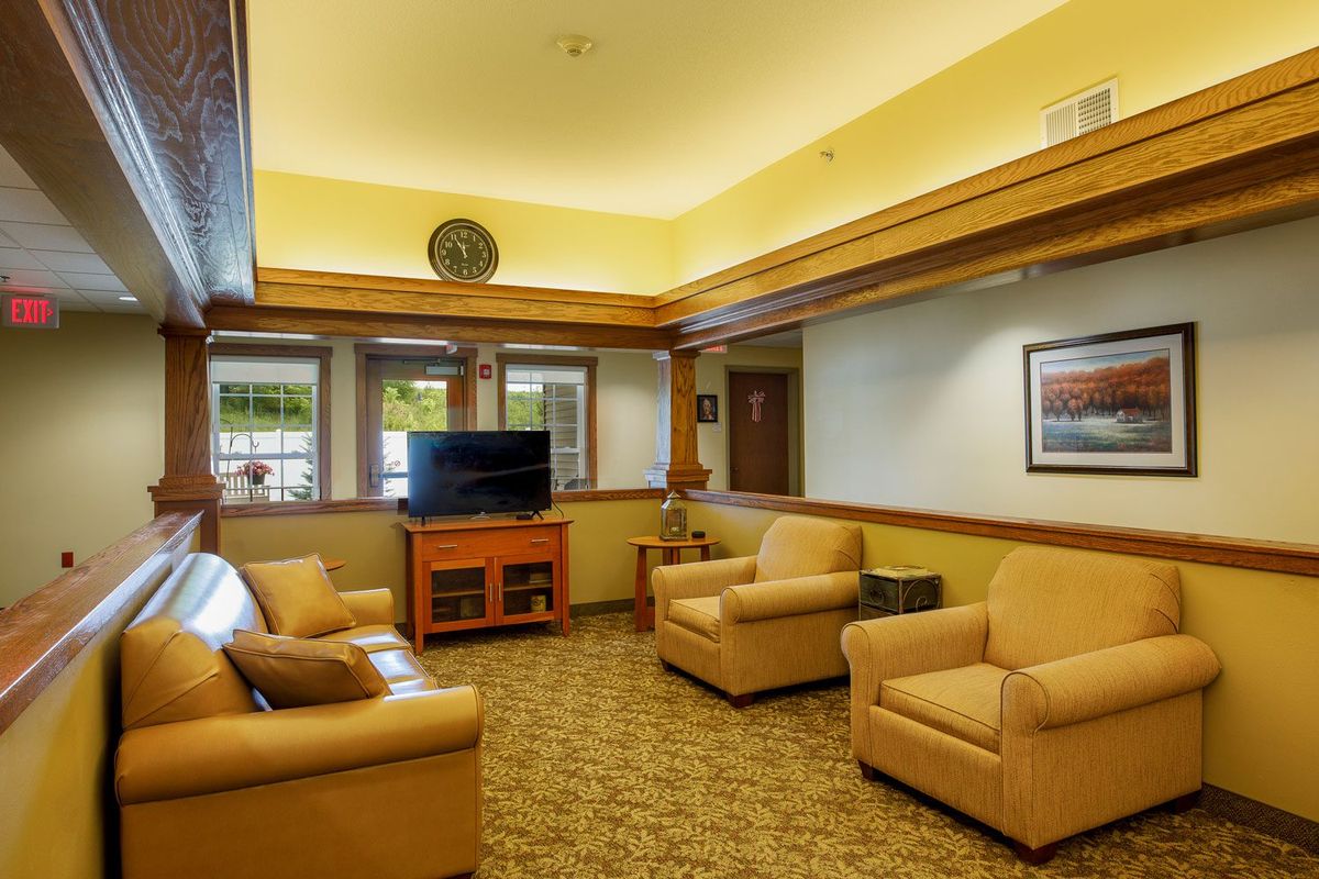 A cozy living room with comfortable seating and a television, featuring warm colors and wood accents.