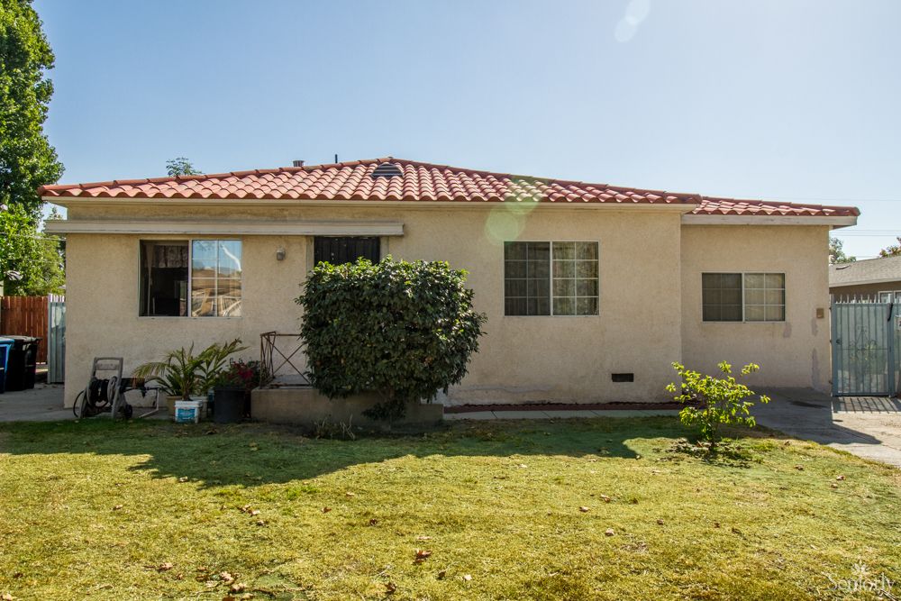 A single-story house with a well-maintained backyard and lush green lawn.