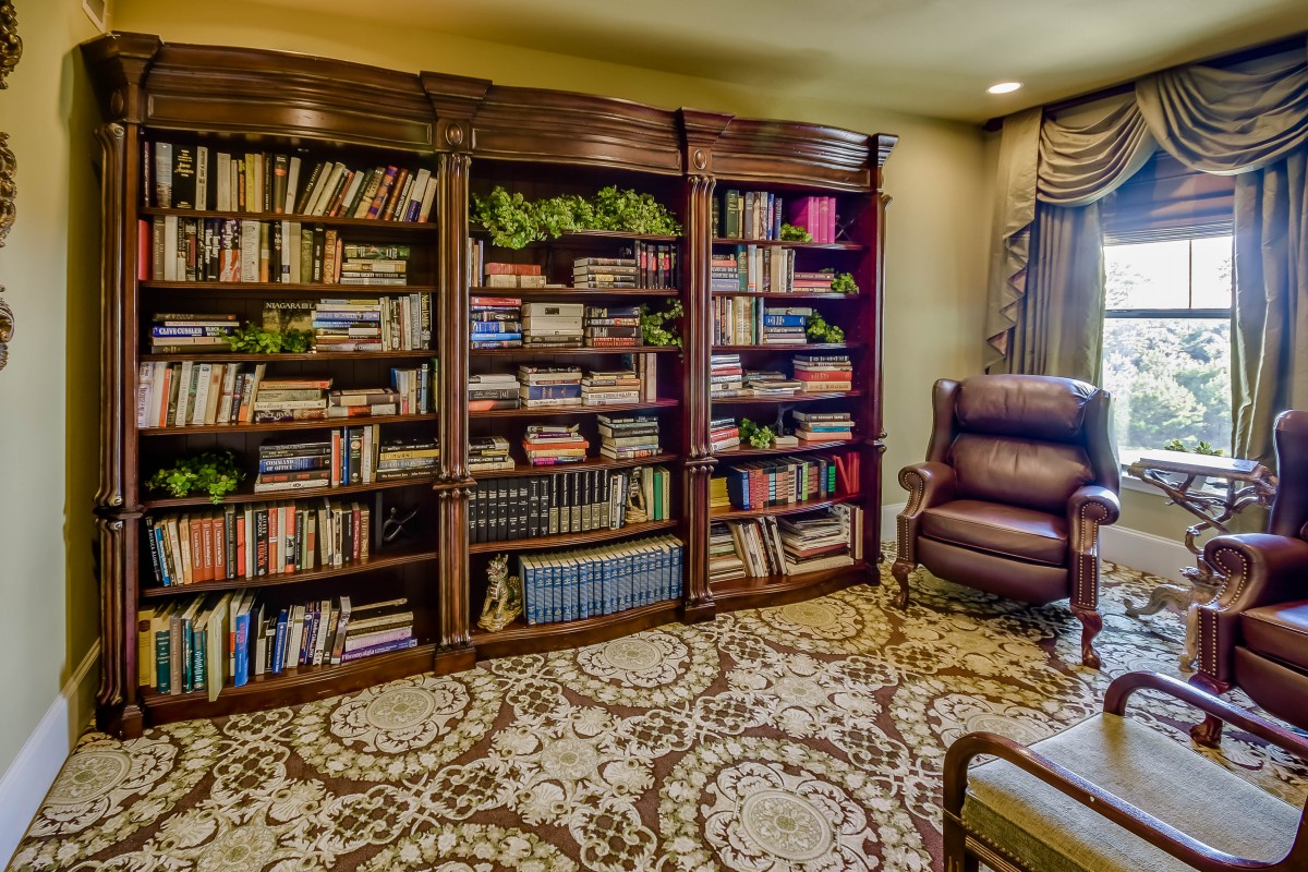 A cozy home library with a large bookshelf filled with books and a comfortable armchair.