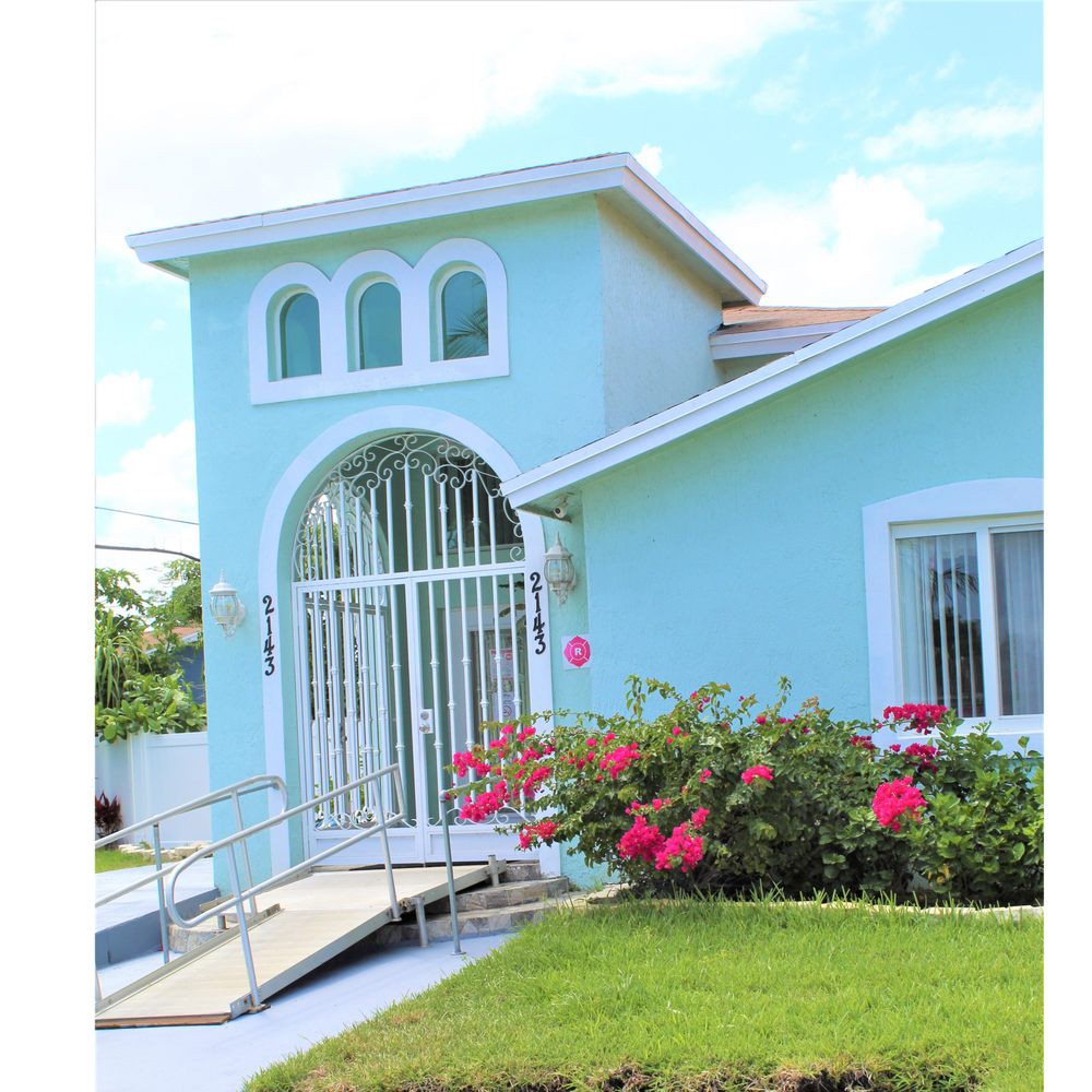 A charming blue house with a well-maintained garden and bright flowers at the entrance.