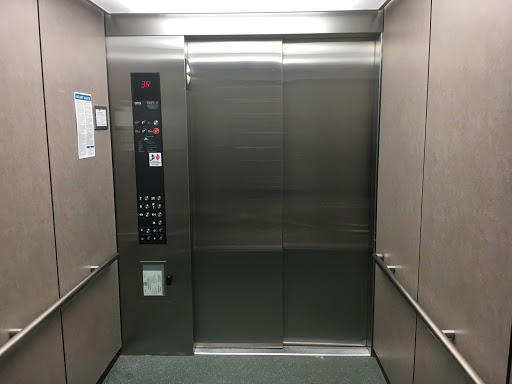 A clean and modern elevator interior showcasing the control panel and stainless steel walls.