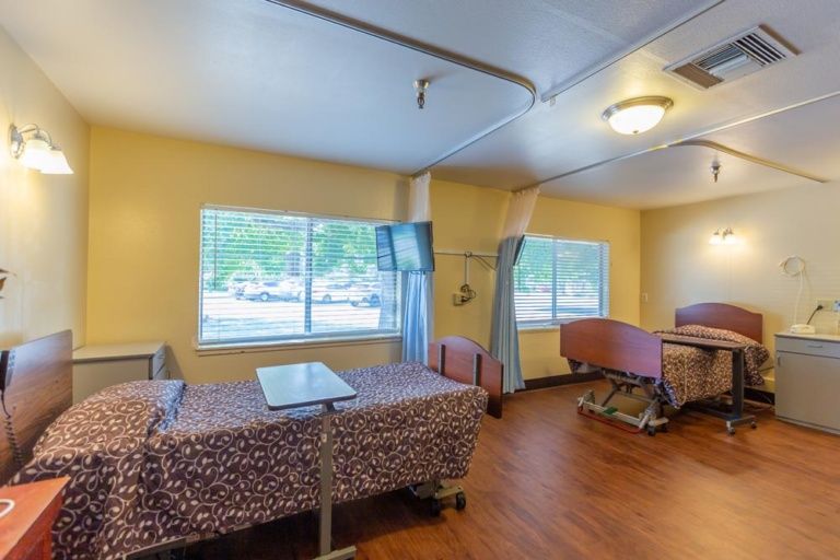 A spacious hospital room with two patient beds and large windows.