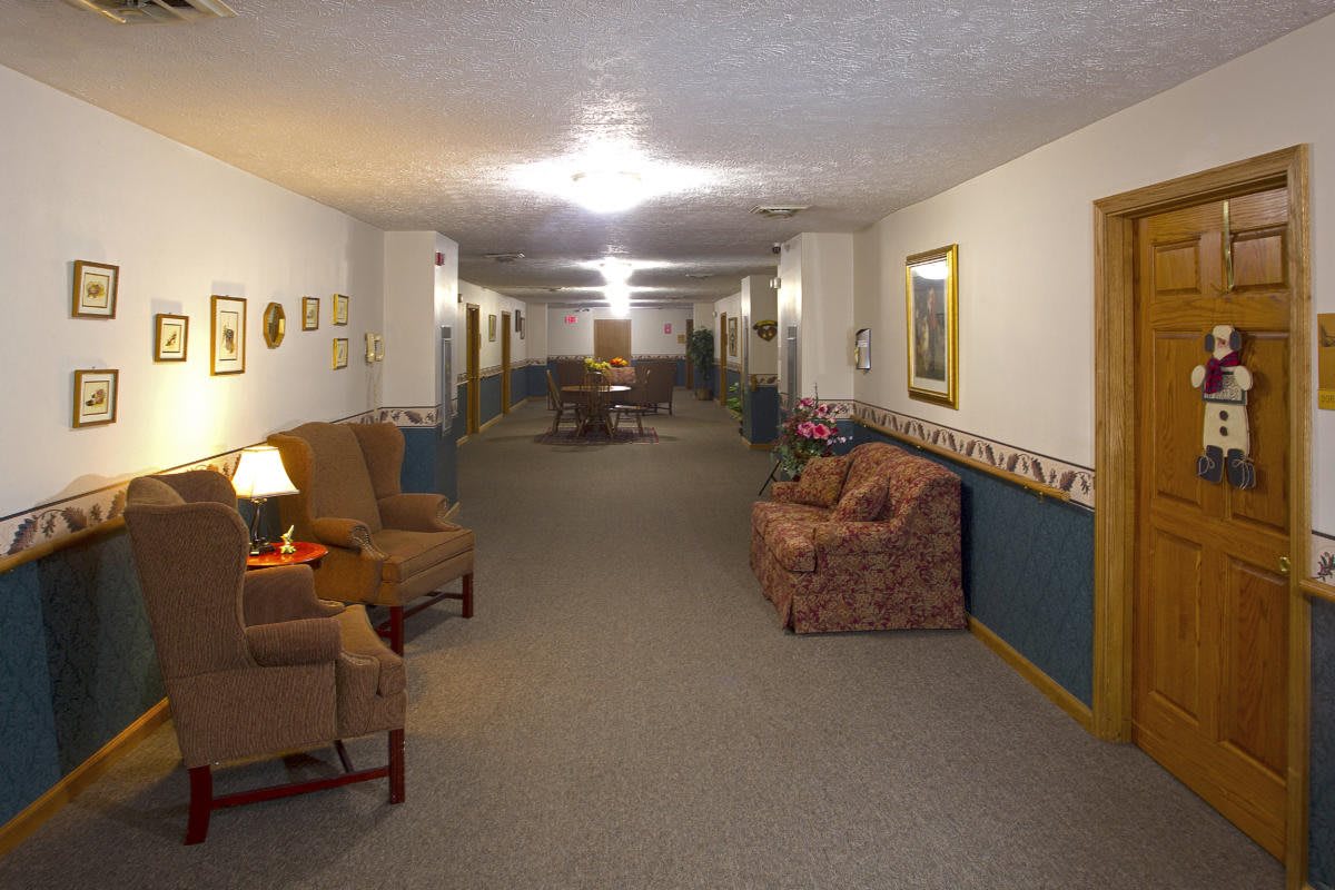 A well-lit hallway with upholstered chairs and sofas along the walls.