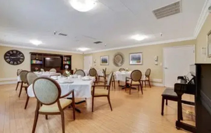 A well-lit dining room with neatly arranged tables and chairs.