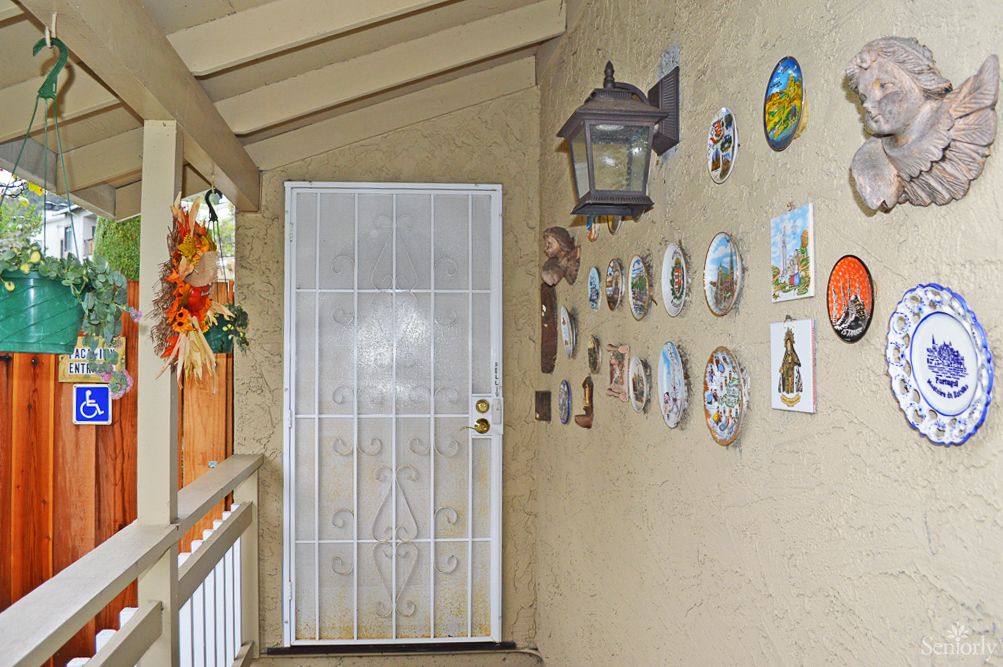 A decorated porch with wall art and a white door.