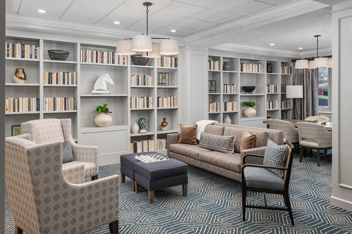 A cozy library room with comfortable seating and neatly arranged bookshelves.