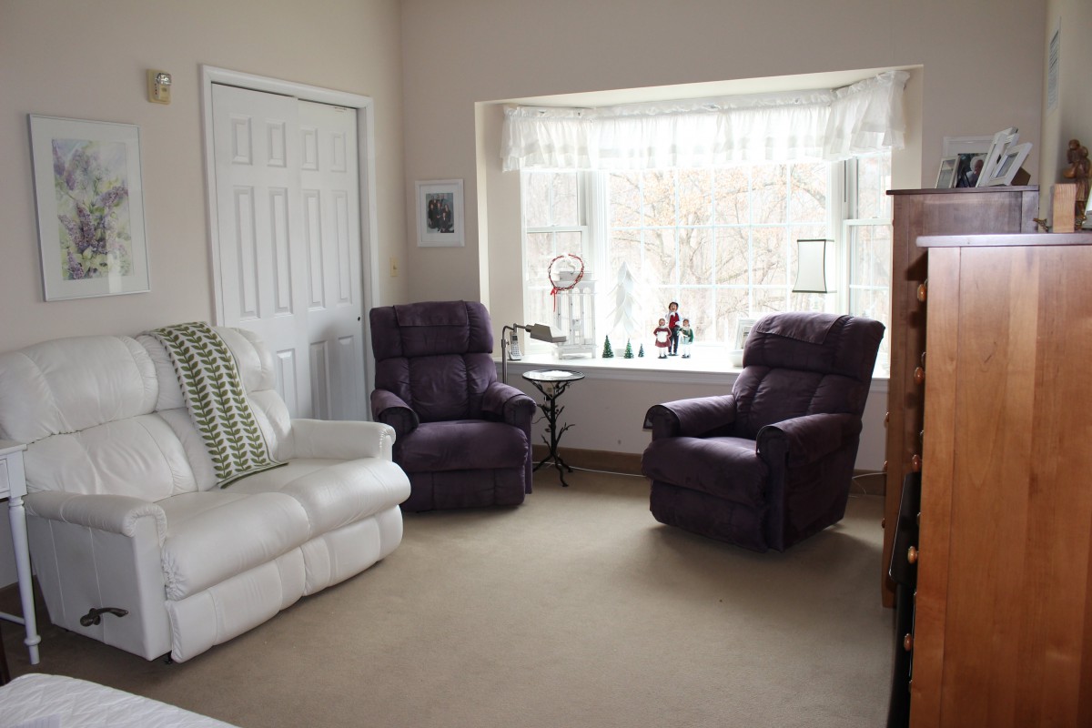 A cozy living room with a large window, two armchairs, and a sofa.