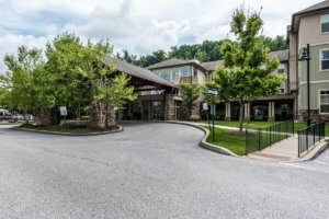An exterior view of a building with a driveway and surrounding greenery.