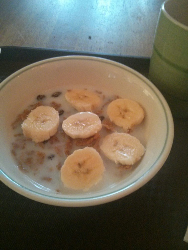 A bowl of cereal with milk and banana slices.