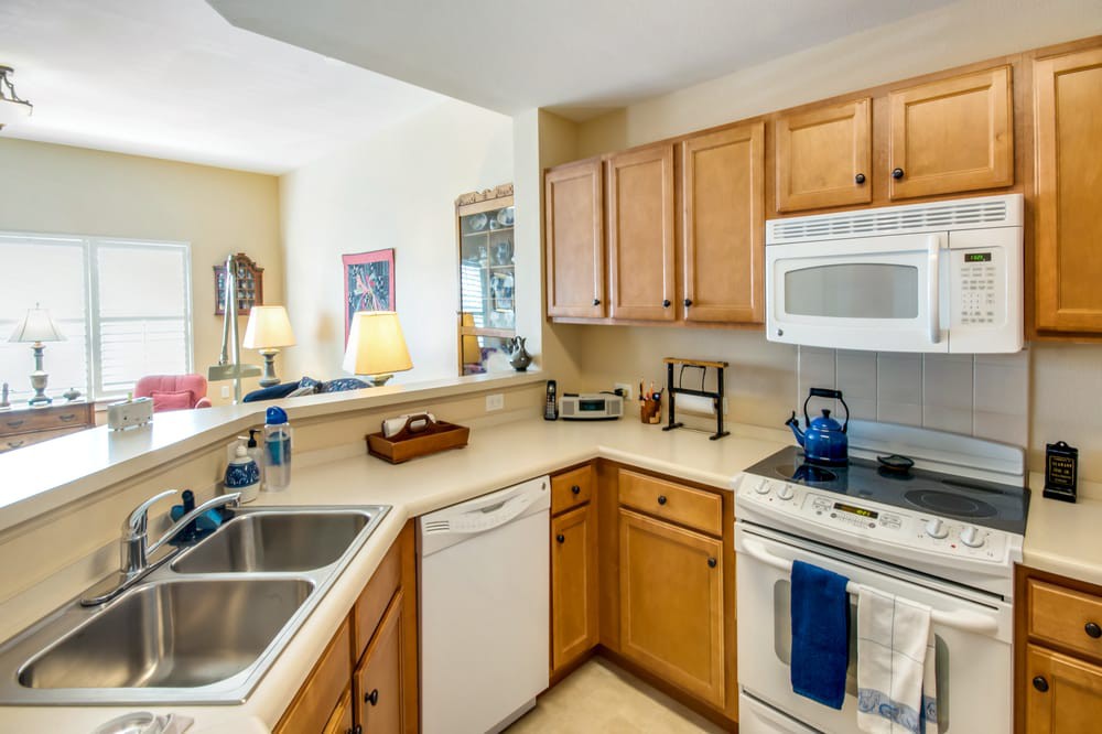 A modern kitchen with wooden cabinets, a double sink, and built-in appliances.