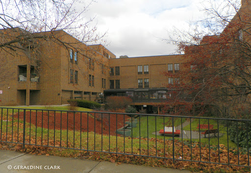 A brick residential building surrounded by autumn foliage and featuring a courtyard.