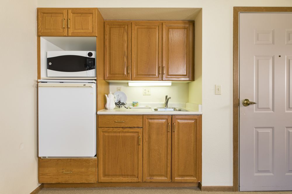 A compact kitchen with wooden cabinets, a built-in oven, and a small sink area.