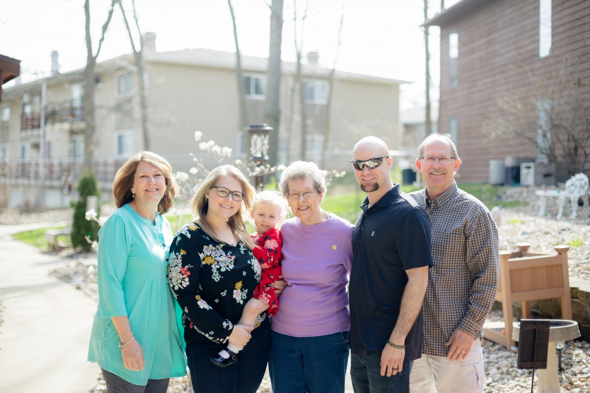 A family group standing together outdoors in casual attire.