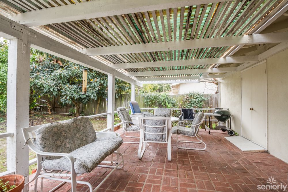 A cozy outdoor patio with seating and a covered roof.