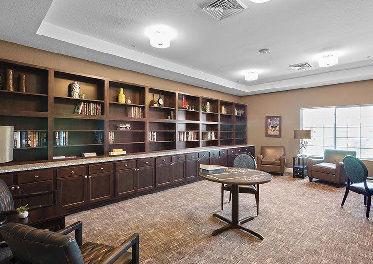 A cozy library space with bookshelves, seating, and a reading table.