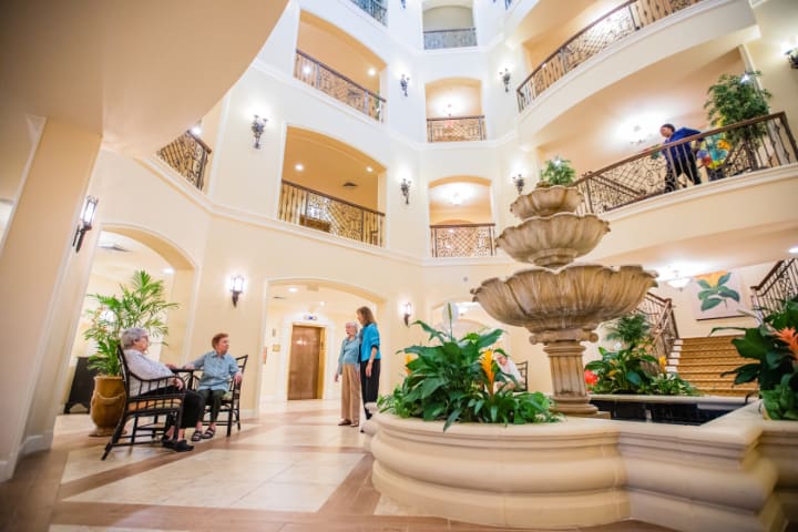 A spacious atrium with a central fountain, surrounded by balconies and people enjoying the ambiance.
