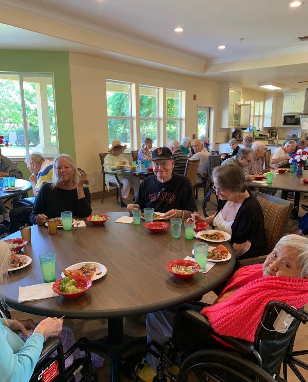 A group of elderly people enjoying a meal together at a community dining table.