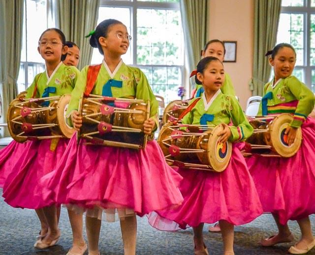 A group of children performing a traditional Korean dance with drums.