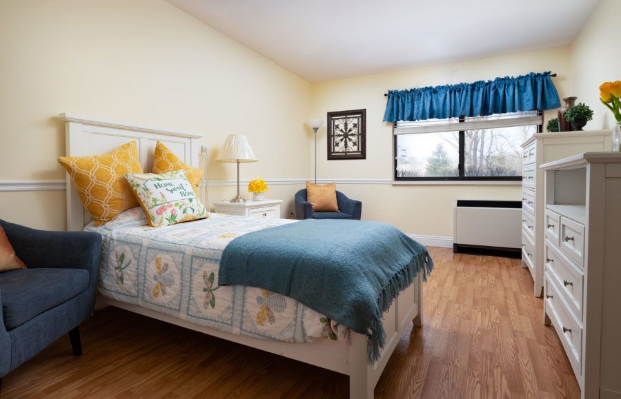 A cozy bedroom with a well-decorated bed, featuring colorful pillows and a blue throw blanket.