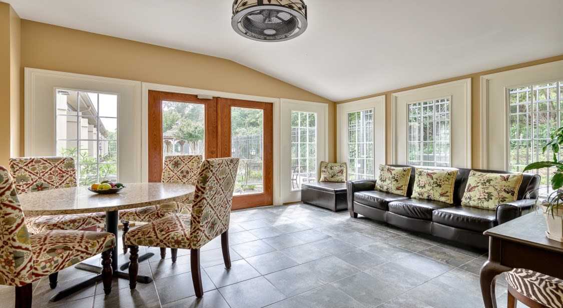 A bright and inviting dining and living area with ample natural light, featuring modern furniture and large windows.