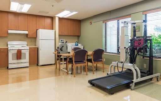 A clean and organized medical clinic space featuring a dining table, chairs, and rehabilitation equipment.